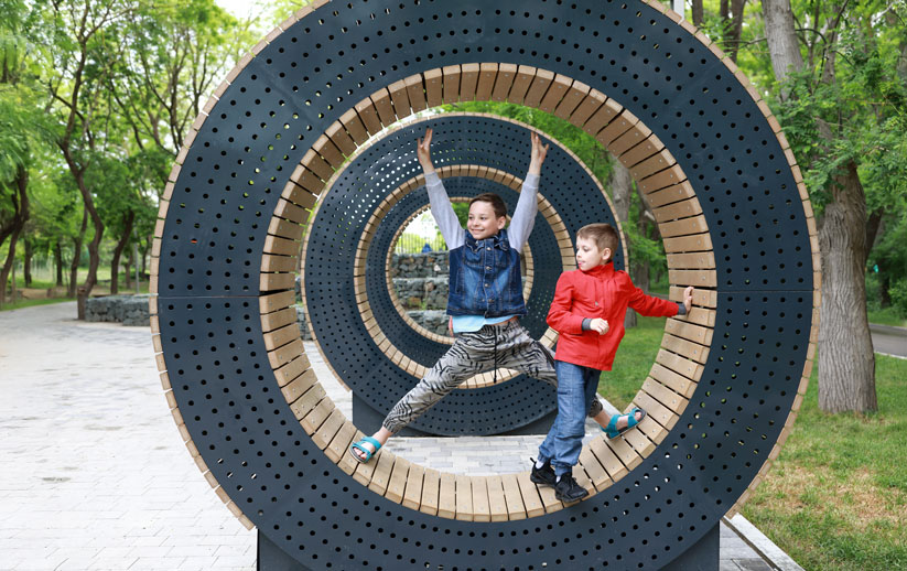 Two children smiling standing on a interactive play public art piece.